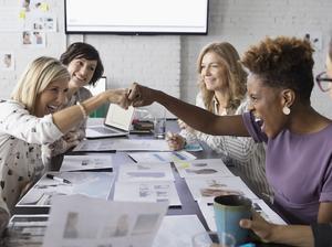 Female designers fist bumping in conference room meeting