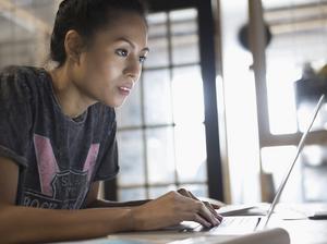 Focused young woman working at laptop in office