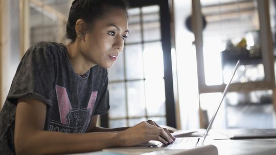 Focused young woman working at laptop in office