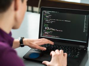 Young man using his laptop to try to solve problem with code