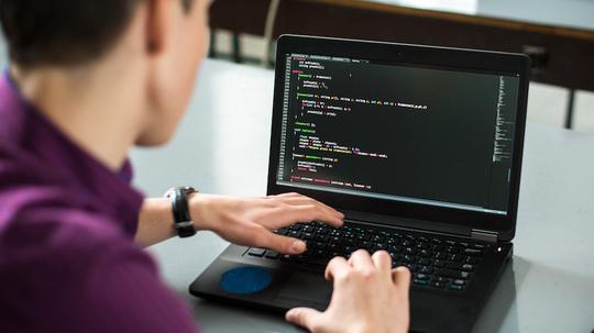 Young man using his laptop to try to solve problem with code