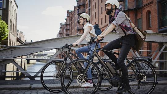 Germany, Hamburg, couple riding electric bicycles at Old Warehouse District