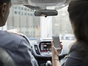 Businesswoman carpooling using cell phone in car