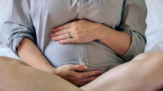 Pregnant Woman Sitting On Bed