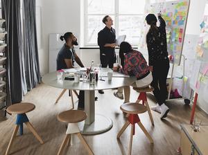 Businesswoman showing colleagues note on whiteboard during meeting in board room