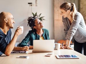 Business colleagues talking while using laptop at office