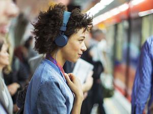 Woman listening to headphones in train station