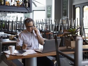 Senior business restaurant doing paperwork at laptop