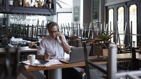 Senior business restaurant doing paperwork at laptop