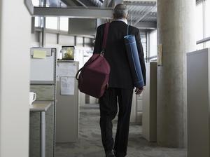 Businessman leaving office with gym bag and yoga mat