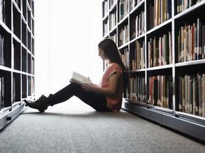 Female student sitting on library floor at college campus