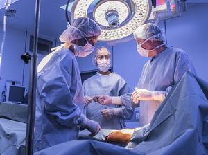 Surgeons operating on patient in operating theatre under lights