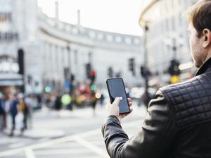 Man checking his phone on the street, rear view