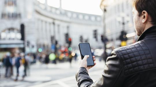 Man checking his phone on the street, rear view