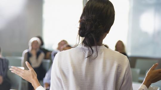 Businesswoman gesturing, leading conference room meeting