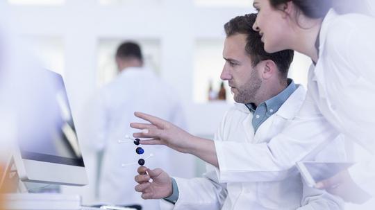 Laboratory workers looking at computer screen