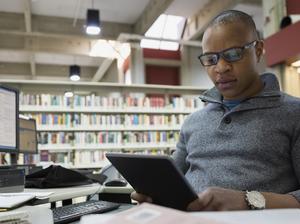 College student studying with digital tablet in library