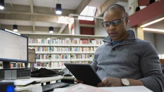 College student studying with digital tablet in library