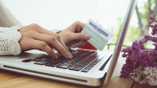 Cropped Hands Of Woman Making Card Payment While Using Laptop At Table