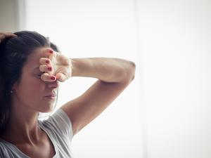 Young woman holding one hand on forehead