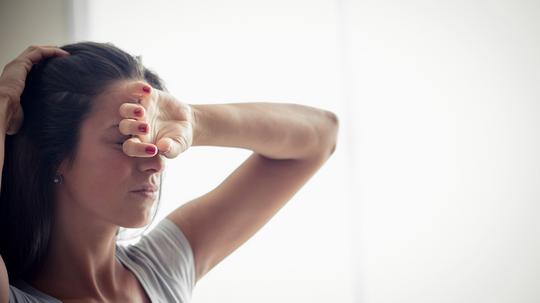 Young woman holding one hand on forehead