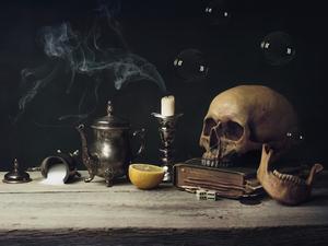 Close-Up Of Human Skull With Lemon And Candle On Table Against Black Background