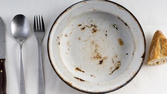 Table prepared with tablecloth, cutlery and metallic plate with a lata of empty conserve