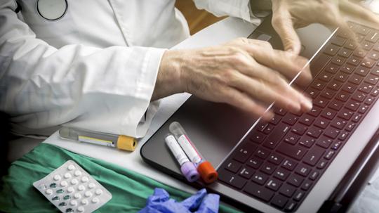 hands of doctor writing fast on laptop, conceptual image