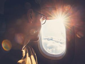 Man Looking Through Airplane Window During Sunny Day