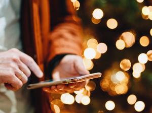 Midsection Of Man Using Smart Phone Against Illuminated Christmas Tree