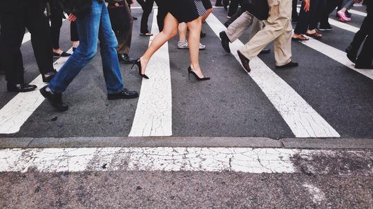 Low Section Of People Walking On Pedestrian Crossing On Street In City