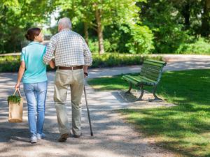 Caregiver – woman with senior man outdoors in the park