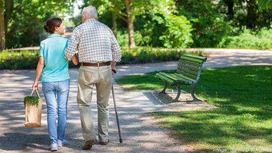 Caregiver – woman with senior man outdoors in the park