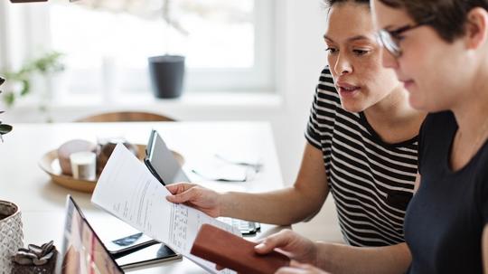 Lesbian couple discussing over financial bills while using laptop at table