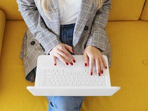 Businesswoman sitting on yellow couch, using laptop