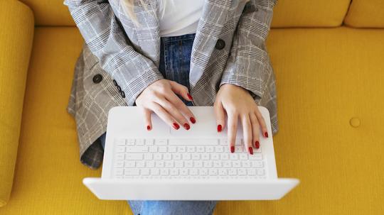 Businesswoman sitting on yellow couch, using laptop