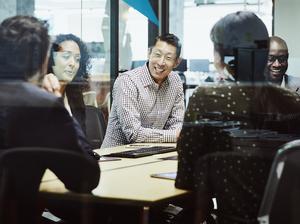 Smiling businessman leading client meeting in office conference room