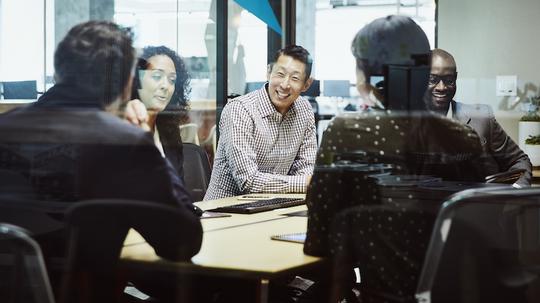 Smiling businessman leading client meeting in office conference room