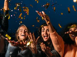 Cheerful Female Friends Throwing Confetti At Night