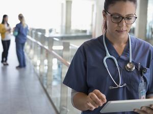 Female nurse using digital tablet in hospital corridor