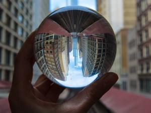 Cropped Hand Holding Crystal Ball With Reflection In City