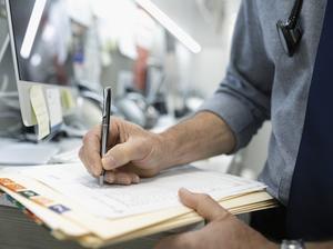 Close up male doctor writing in medical record