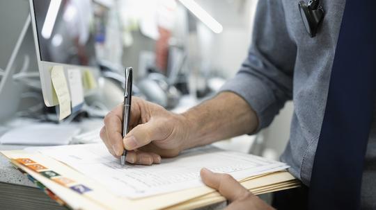 Close up male doctor writing in medical record