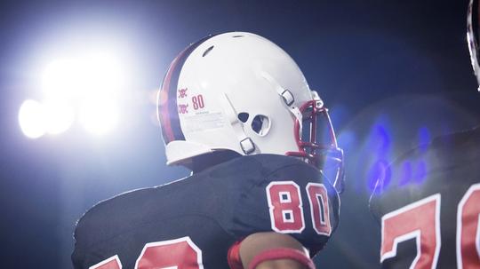 Low angle view of American football players against sky at night