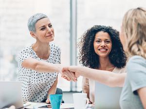 Businesswomen shaking hands over the table