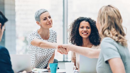 Businesswomen shaking hands over the table