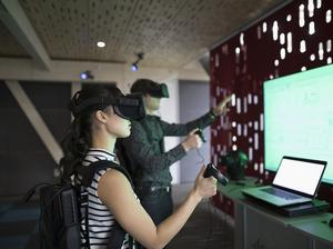 Computer programmers testing virtual reality simulator glasses and joysticks in office