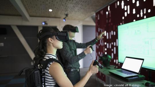 Computer programmers testing virtual reality simulator glasses and joysticks in office