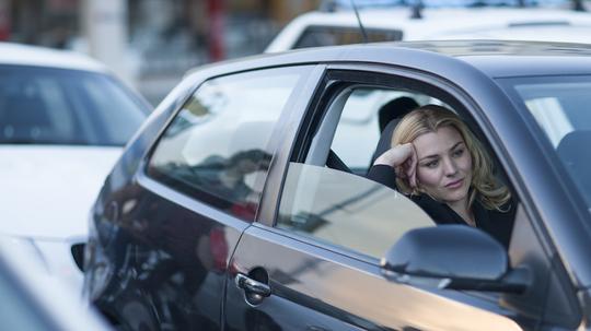 Bored businesswoman driving in city traffic jam