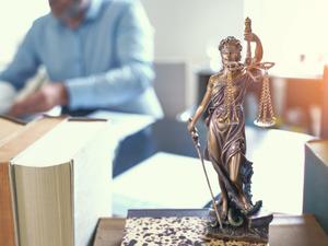 Close-Up Of Lady Justice On Table With Lawyer In Background At Office